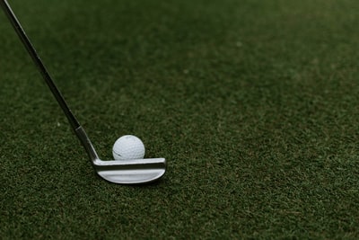 绿色草地上高尔夫球旁的黑色和灰色高尔夫球杆
